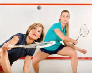 Two female squash players in action on court – representing inclusive and competitive play.