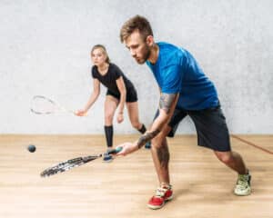 Male and female squash players in action on court – representing inclusive play and competitive spirit.