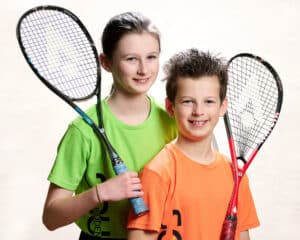 Two junior players on court with their rackets at Biddenden Squash Club in Kent, an England Squash-affiliated club.